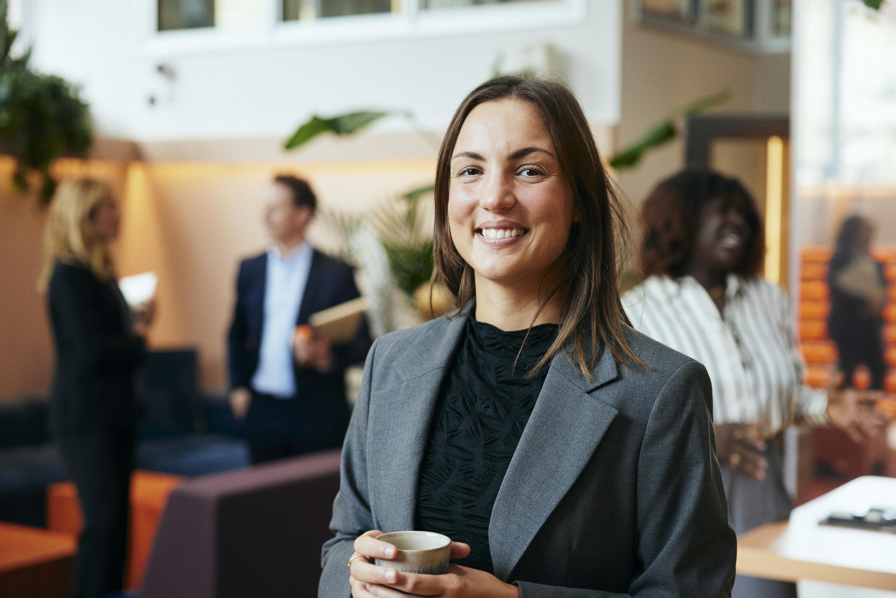 En kvinna håller en kaffekopp i lobbyn på ett kontor