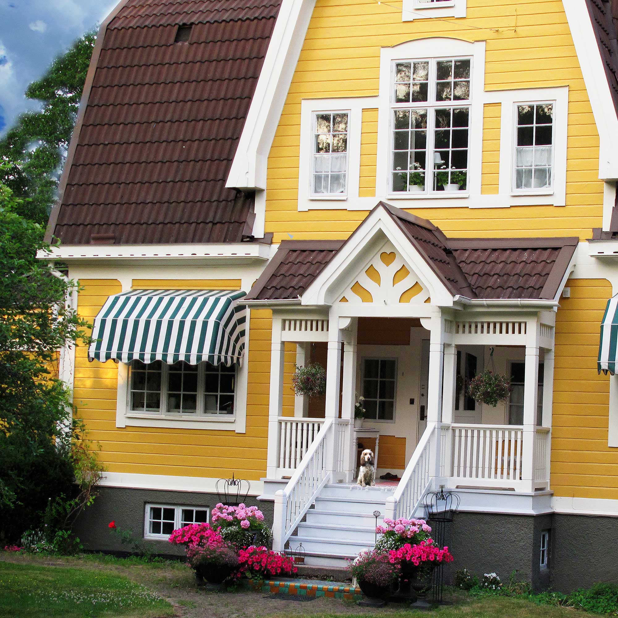 en bild på ett gult trähus med trädgård framför
