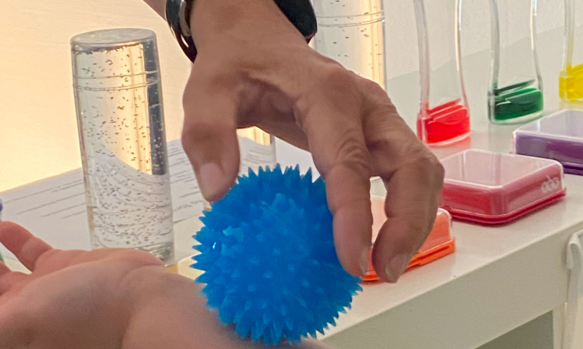 bild på en blå boll som en hand rullar längst ett barns arm